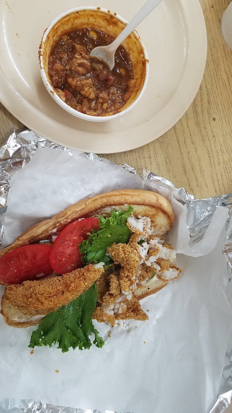 Fried fish po'boy with tomato and lettuce next to a bowl of gumbo